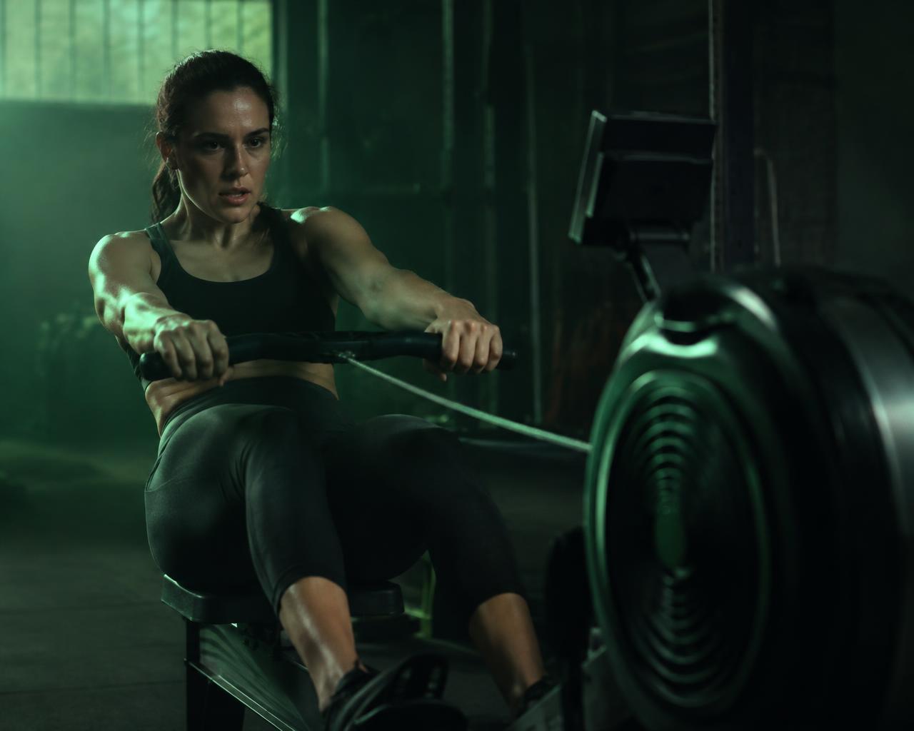 An athlete pulling hard on an indoor rowing machine