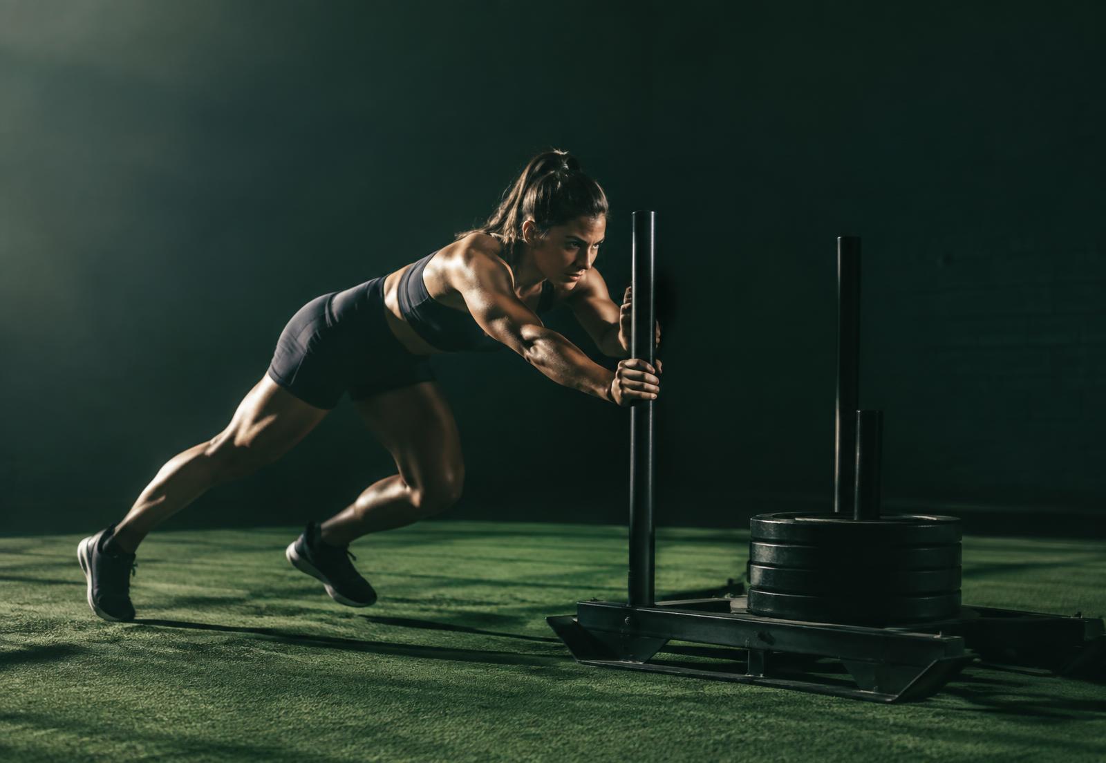 An athlete driving a weighted sled across turf